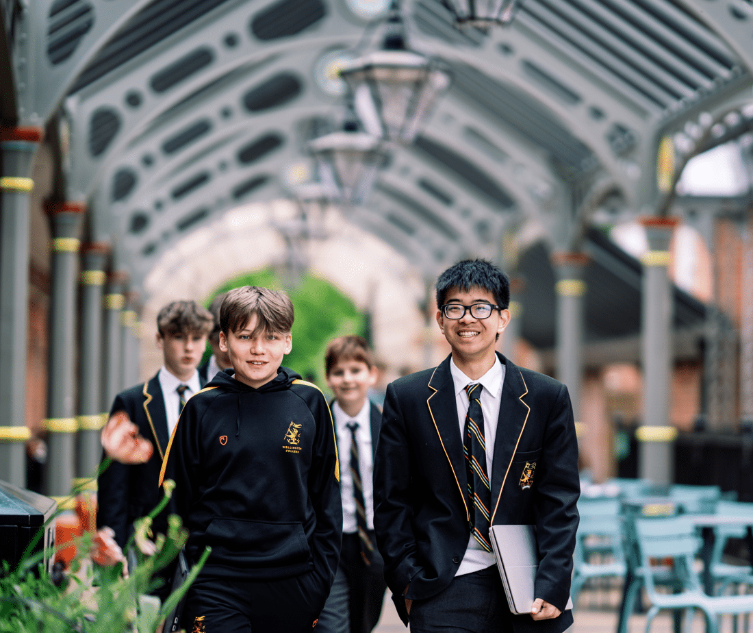 Three Wellington students standing in an arched stone cloister